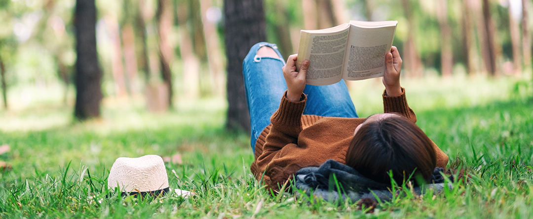books-01 a girl laying in grass with a book